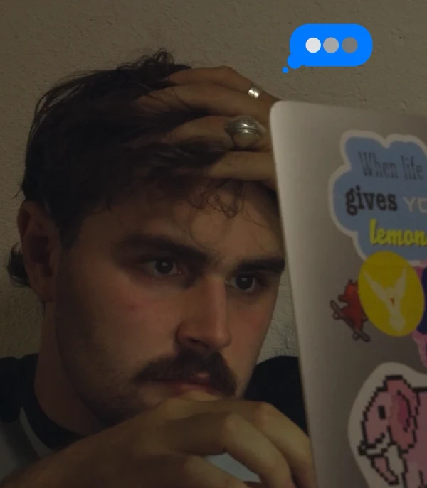 Aaron sitting at his desk, hand in his hair, staring at his laptop